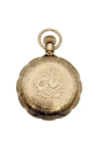 Ornate gold pocket watch with engraved floral design on the case and a ring at the crown